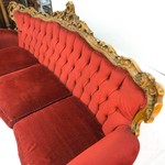 Старинный диван с красной бархатной обивкой и каретной стяжкой